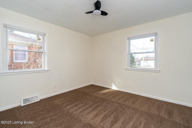 carpeted empty room with a ceiling fan, visible vents, and baseboards