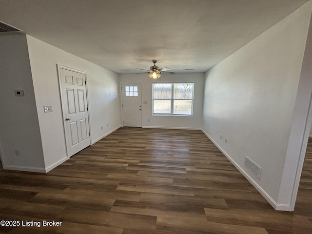 interior space with dark wood-type flooring, visible vents, baseboards, and a ceiling fan