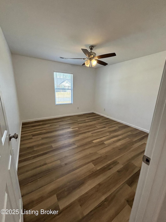 empty room with dark wood-style floors, ceiling fan, and baseboards