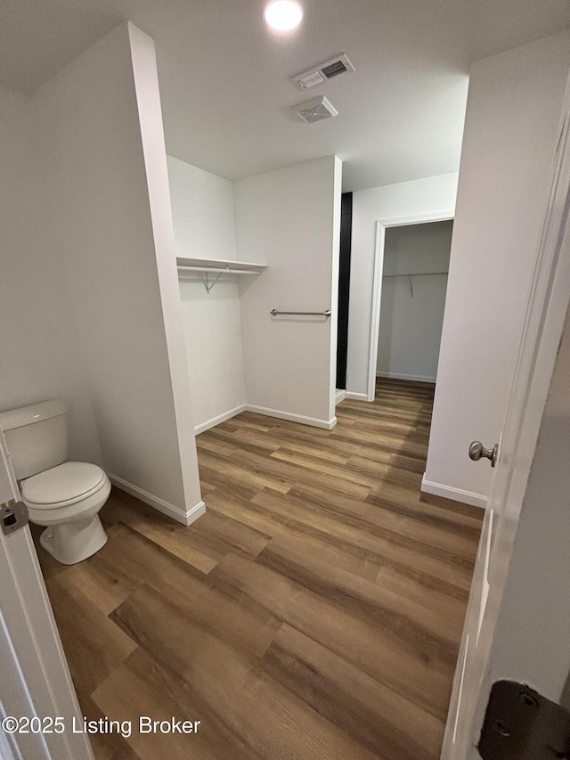 bathroom featuring toilet, baseboards, visible vents, and wood finished floors