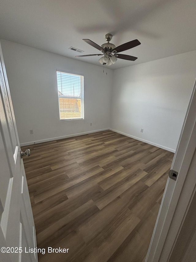 empty room with a ceiling fan, dark wood-style flooring, visible vents, and baseboards