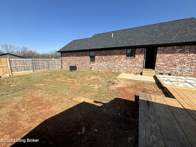 view of yard with entry steps, fence, and central AC