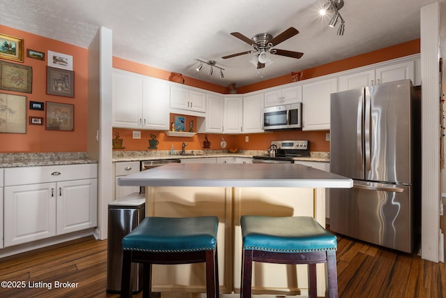 kitchen featuring stainless steel appliances, white cabinetry, dark wood finished floors, and ceiling fan