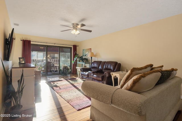 living area with a ceiling fan, a textured ceiling, visible vents, and wood finished floors