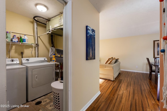 laundry area featuring washer and clothes dryer, a textured ceiling, wood finished floors, laundry area, and baseboards