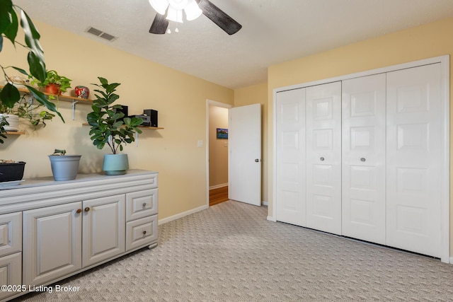 interior space featuring a ceiling fan, visible vents, light carpet, and baseboards