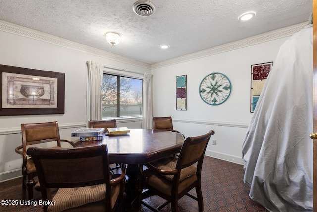 dining space with a textured ceiling, crown molding, visible vents, and baseboards