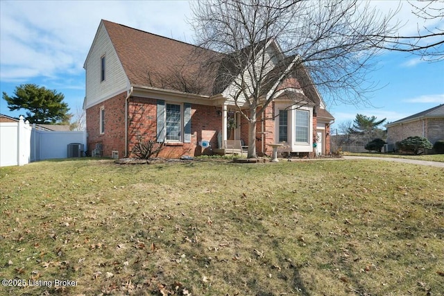 view of front of property featuring brick siding, a front lawn, central AC unit, and fence