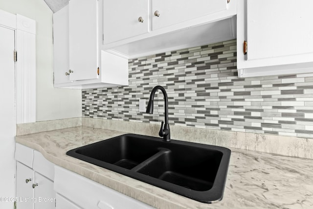 kitchen featuring white cabinets, light countertops, a sink, and backsplash