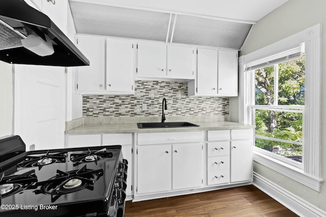 kitchen featuring light countertops, a sink, black gas stove, and under cabinet range hood