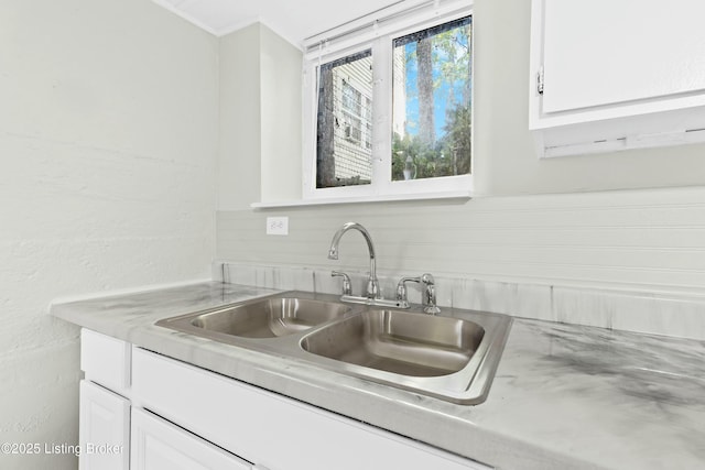 kitchen featuring light countertops, a sink, and white cabinetry