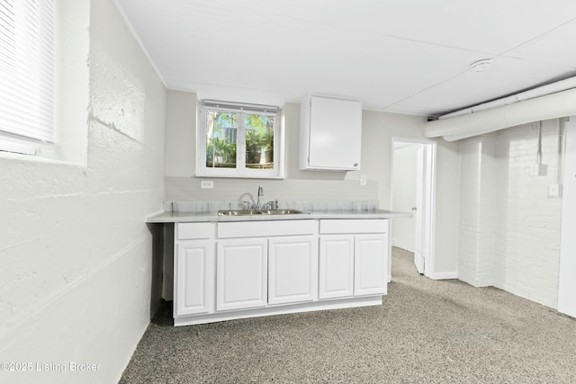 kitchen with light countertops, a sink, white cabinetry, and light colored carpet