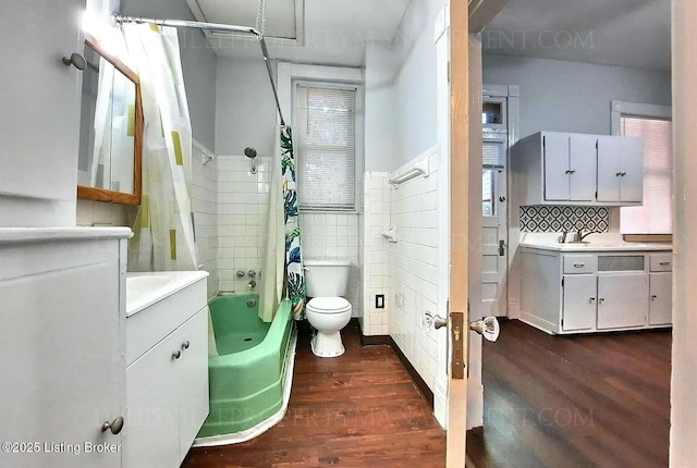 full bath with tile walls, shower / bathtub combination with curtain, toilet, vanity, and wood finished floors