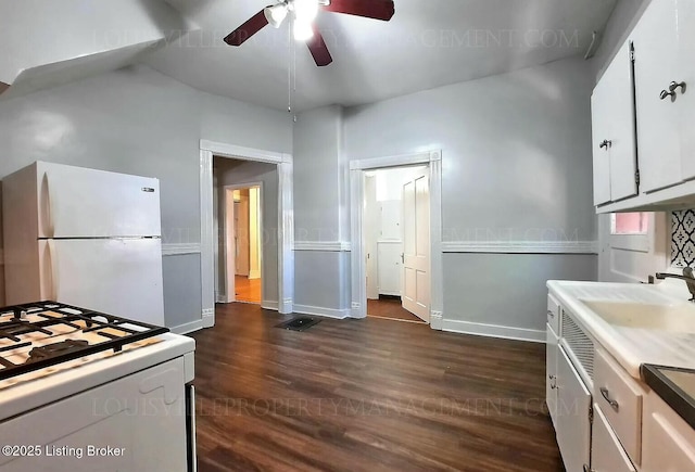 kitchen with white appliances, baseboards, white cabinets, a ceiling fan, and dark wood-style flooring