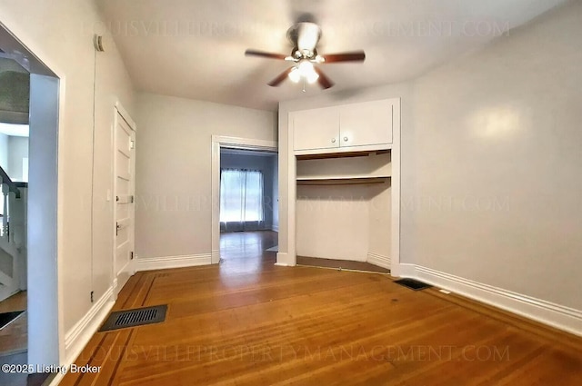 interior space featuring visible vents, ceiling fan, baseboards, and wood finished floors