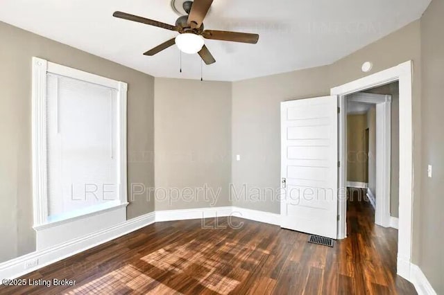 unfurnished room with a ceiling fan, visible vents, baseboards, and wood finished floors