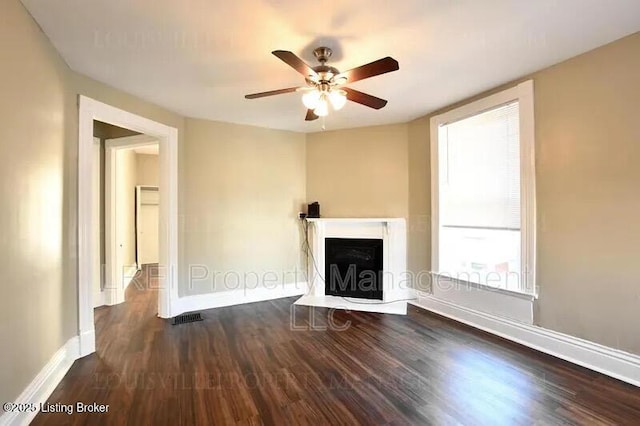 unfurnished living room featuring a fireplace with raised hearth, baseboards, and wood finished floors