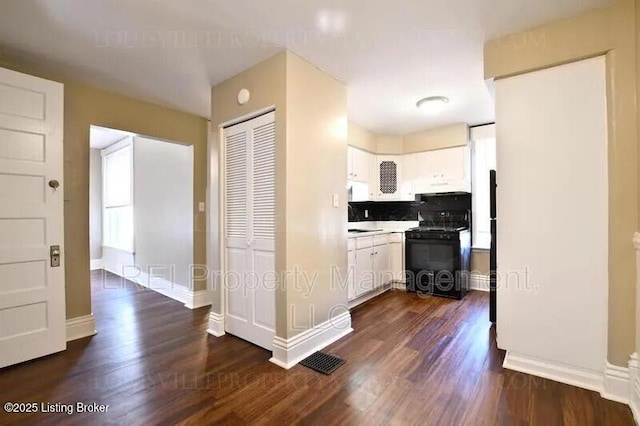 kitchen featuring white cabinetry, dark wood finished floors, baseboards, and black range with gas stovetop