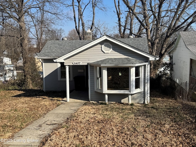 bungalow with a shingled roof and a front yard