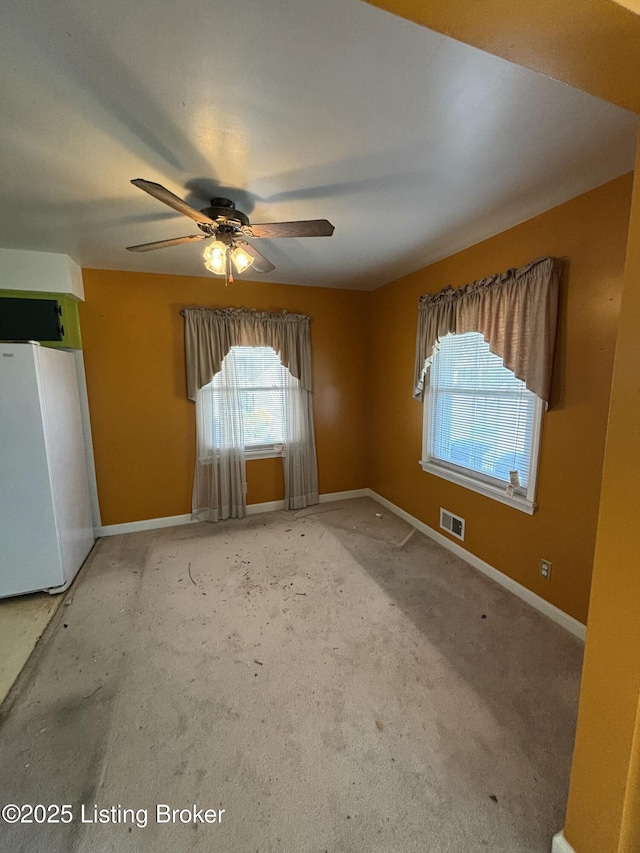 unfurnished room with a ceiling fan, carpet, visible vents, and baseboards