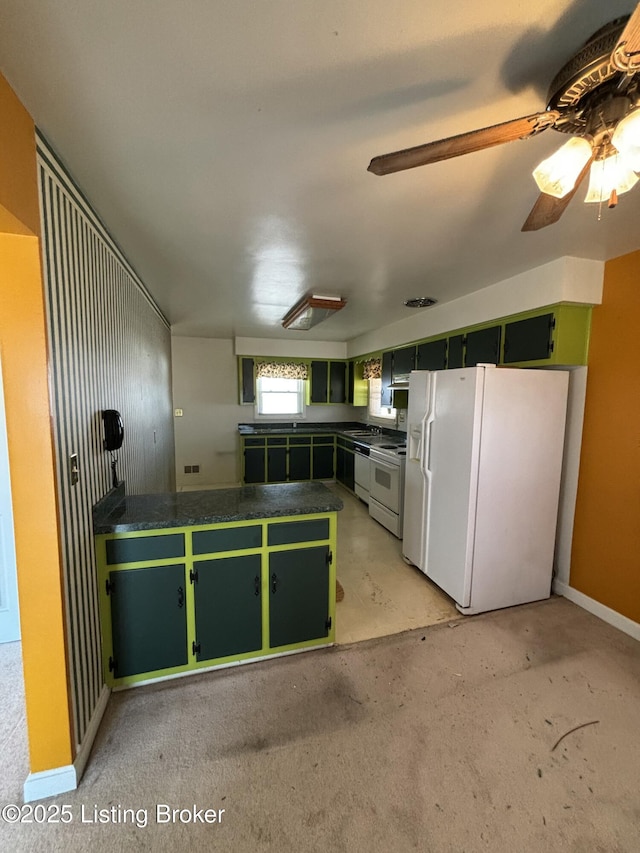 kitchen featuring white appliances, baseboards, dark countertops, a peninsula, and green cabinetry