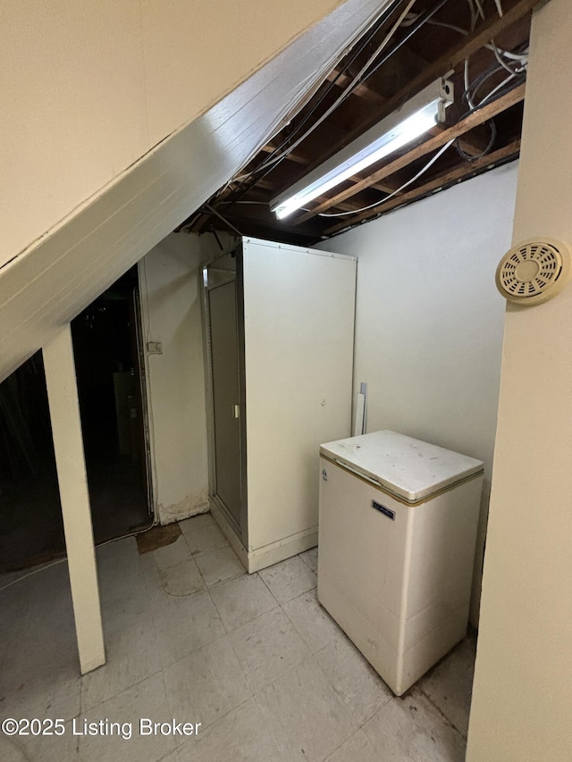 unfinished basement featuring fridge