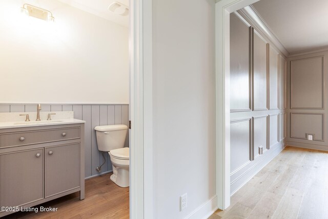 3314 Catalpa Farms Dr, Fisherville, KY 40023 - bathroom with toilet, wood finished floors, vanity, a wainscoted wall, and a decorative wall