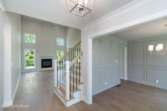3314 Catalpa Farms Dr, Fisherville, KY 40023 - staircase featuring wood finished floors, a chandelier, a decorative wall, a glass covered fireplace, and baseboards