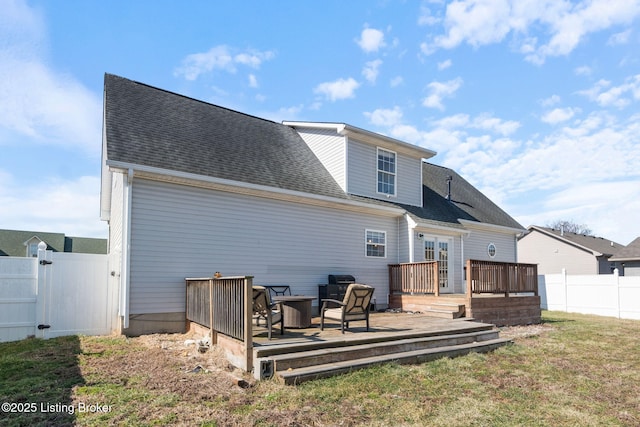 rear view of property with a shingled roof, a lawn, a gate, fence, and a wooden deck