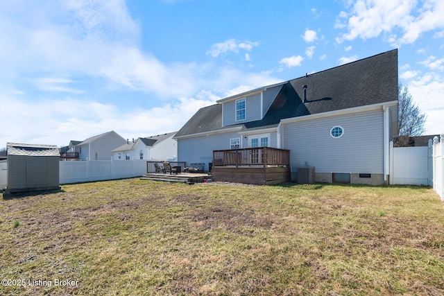 rear view of property with an outbuilding, a yard, a shed, a fenced backyard, and a wooden deck