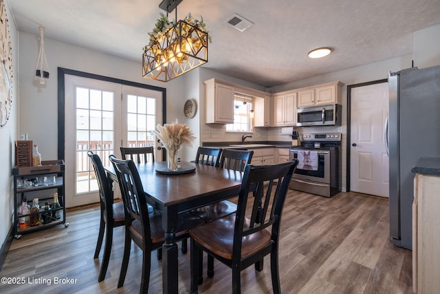 dining space featuring a wealth of natural light, visible vents, and wood finished floors