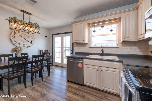 kitchen with appliances with stainless steel finishes, dark countertops, dark wood-type flooring, and a sink