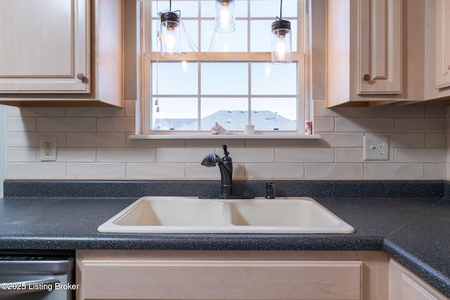 kitchen featuring dishwasher, tasteful backsplash, dark countertops, and a sink