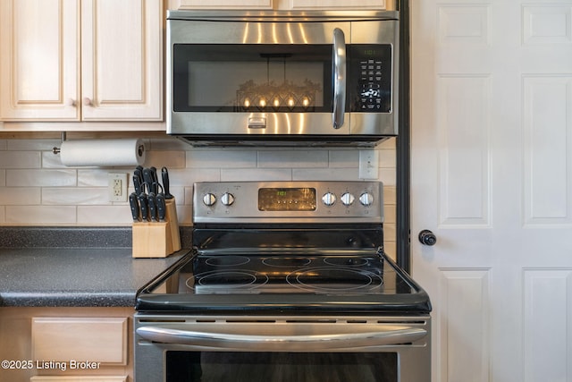 details with dark countertops, cream cabinets, appliances with stainless steel finishes, and decorative backsplash