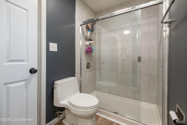 full bathroom with wood finished floors, a shower stall, and toilet