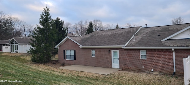 rear view of house with a patio area, roof with shingles, a lawn, and brick siding