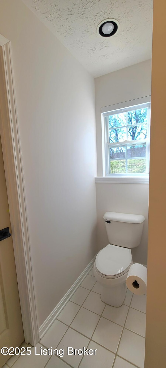 bathroom featuring toilet, baseboards, a textured ceiling, and tile patterned floors