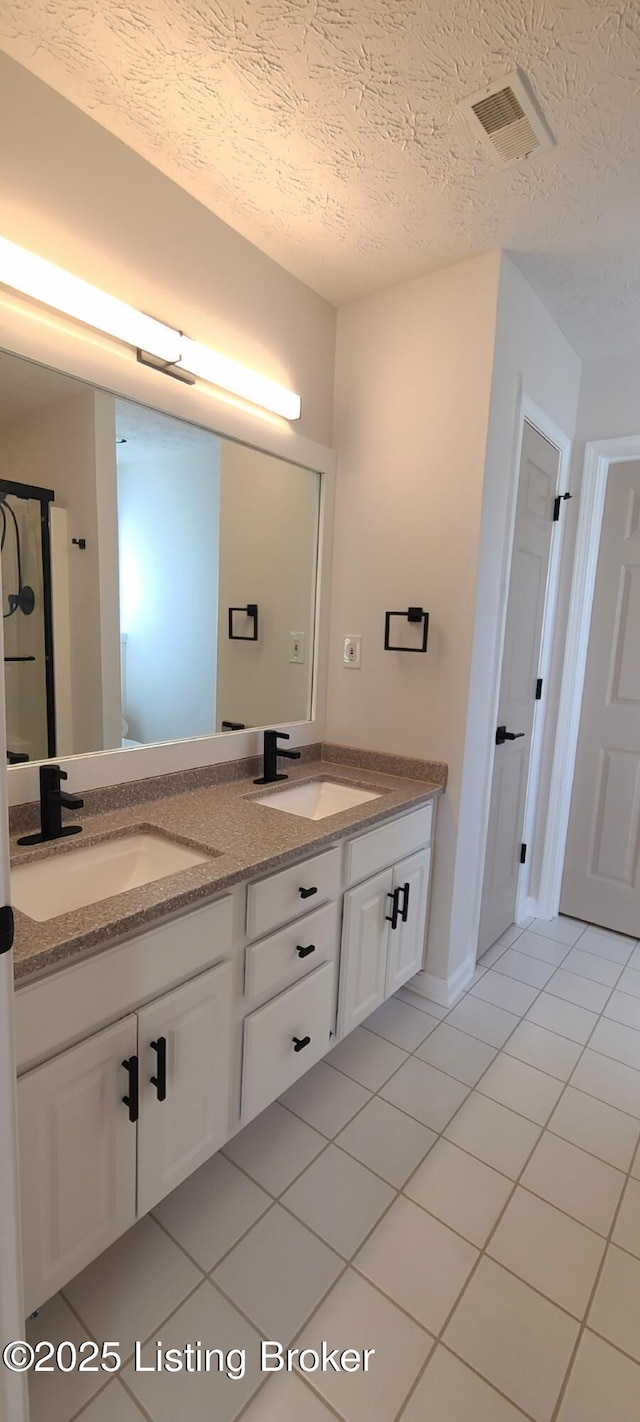 bathroom with double vanity, visible vents, a sink, and tile patterned floors