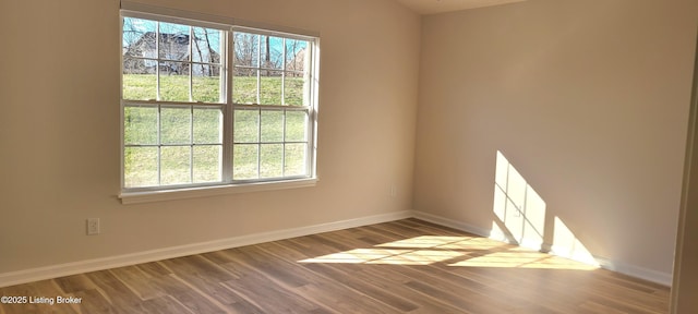 spare room featuring baseboards and wood finished floors