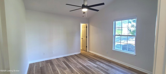 spare room featuring dark wood-style floors, ceiling fan, baseboards, and vaulted ceiling