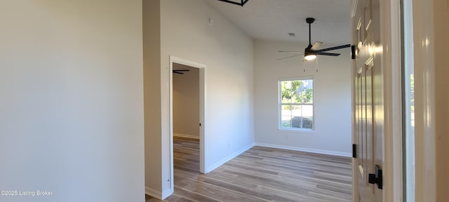 unfurnished room with visible vents, a towering ceiling, light wood-style flooring, ceiling fan, and baseboards