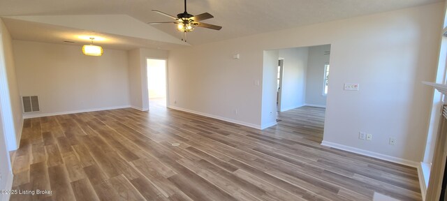 empty room featuring visible vents, ceiling fan, vaulted ceiling, wood finished floors, and baseboards