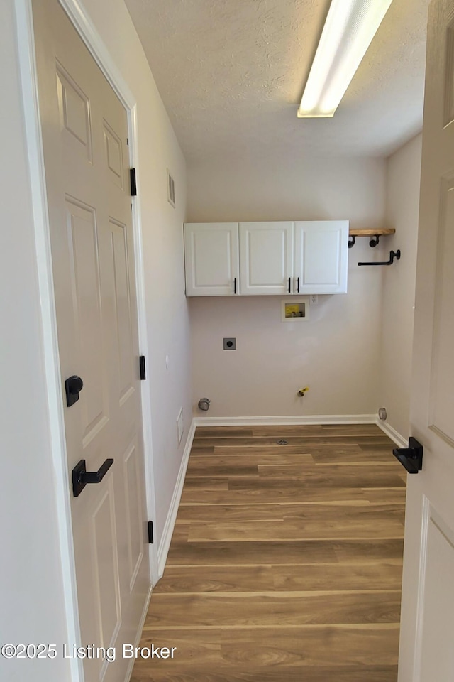 clothes washing area featuring washer hookup, wood finished floors, visible vents, baseboards, and cabinet space