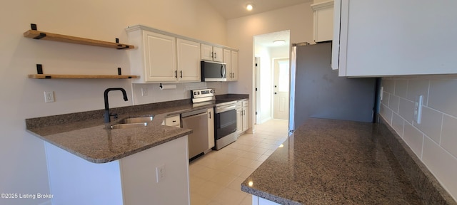 kitchen featuring stainless steel appliances, a peninsula, a sink, white cabinetry, and open shelves