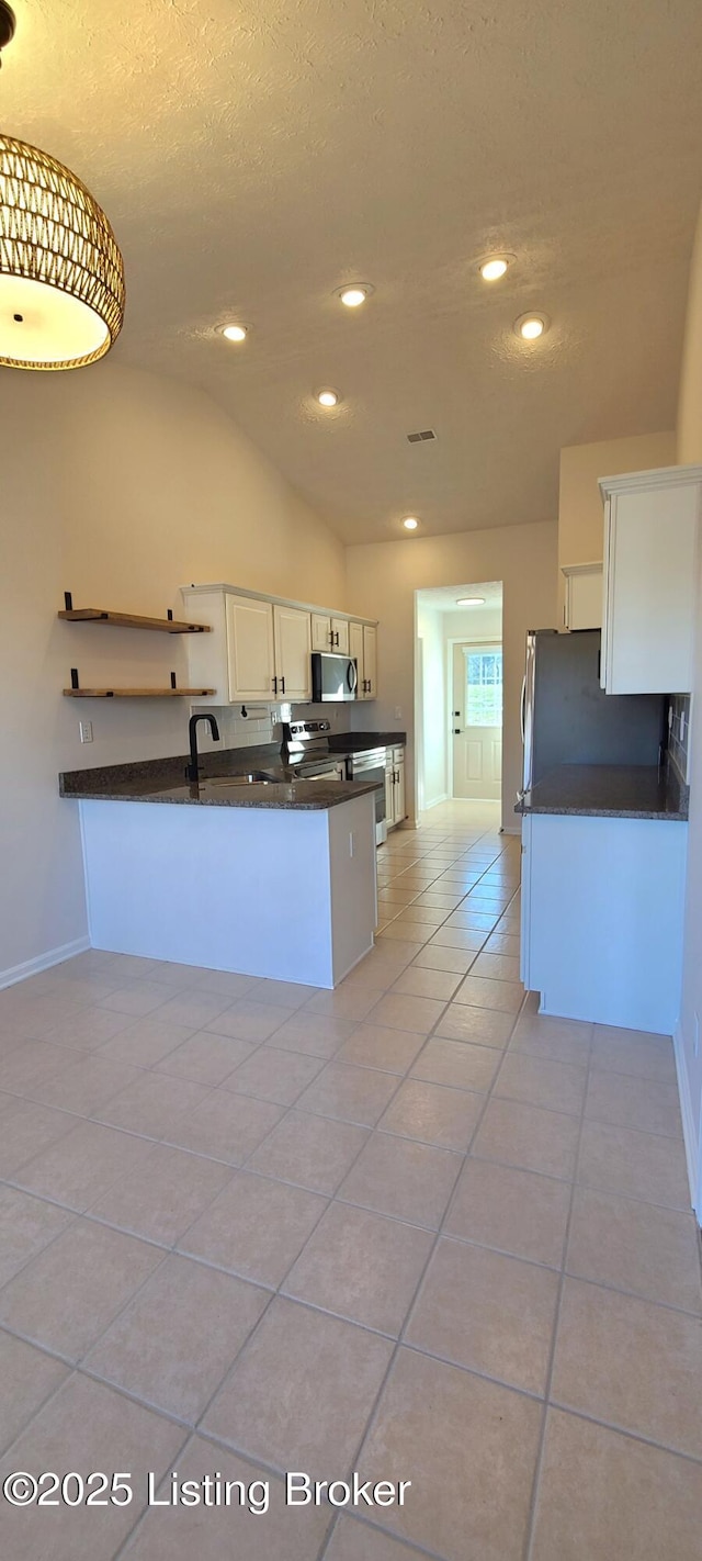 kitchen with light tile patterned floors, recessed lighting, appliances with stainless steel finishes, white cabinetry, and vaulted ceiling