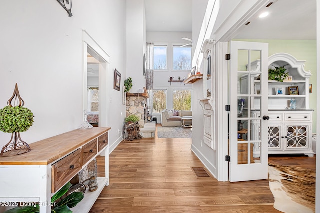 interior space with a high ceiling, wood finished floors, and visible vents