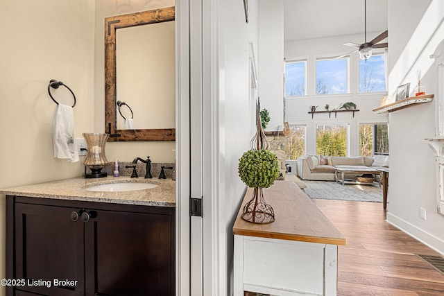 bathroom with visible vents, a ceiling fan, wood finished floors, a high ceiling, and vanity