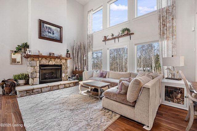 living room with a wealth of natural light, a stone fireplace, and wood finished floors