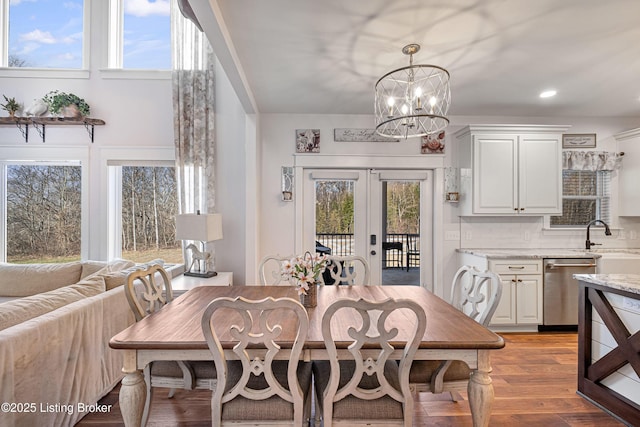 dining area with french doors, a healthy amount of sunlight, an inviting chandelier, and wood finished floors