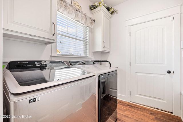 clothes washing area with cabinet space, washer and dryer, and wood finished floors